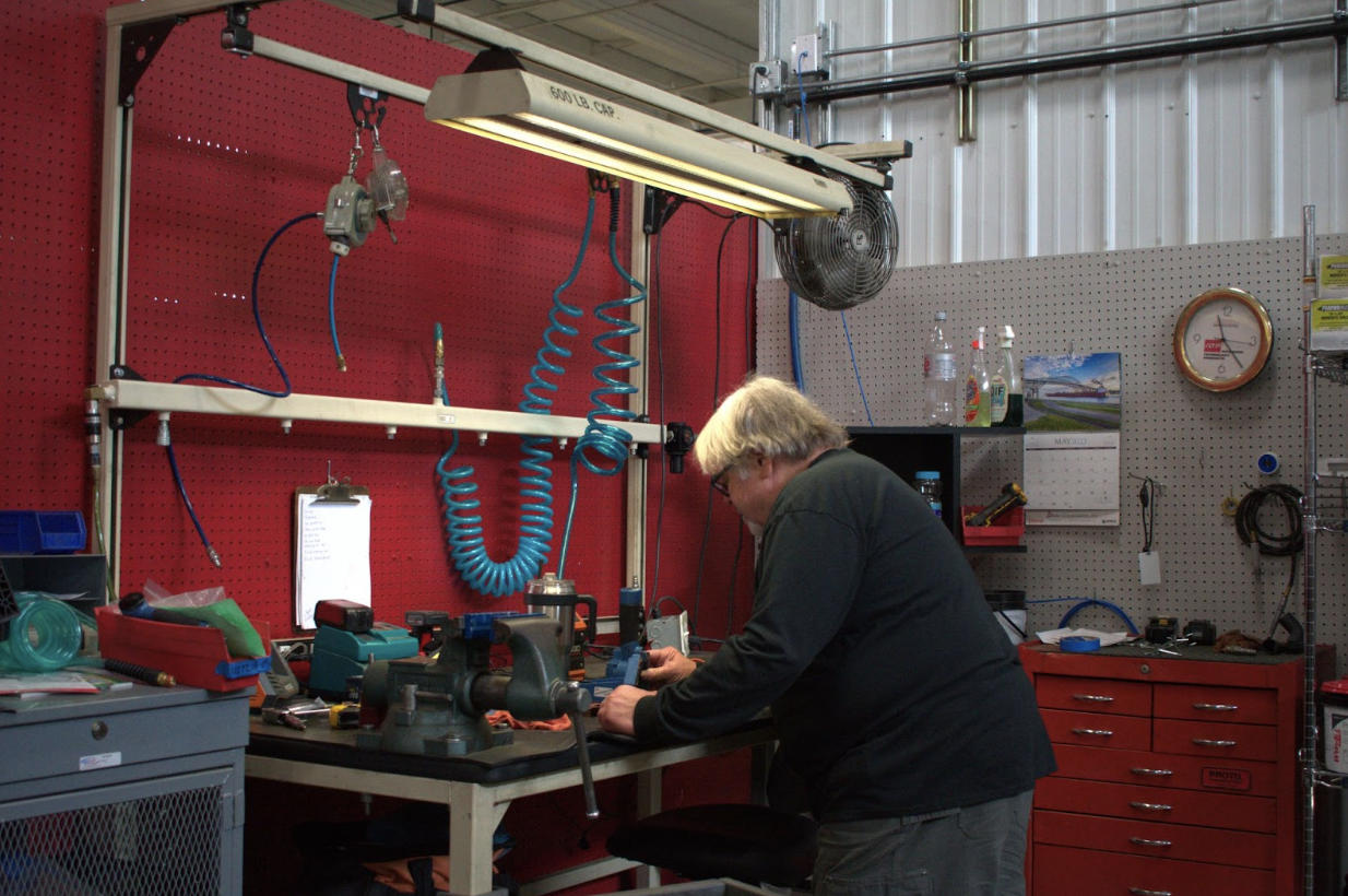 Worker efficiently assembling products in a well-organized work cell, surrounded by essential tools and equipment. 